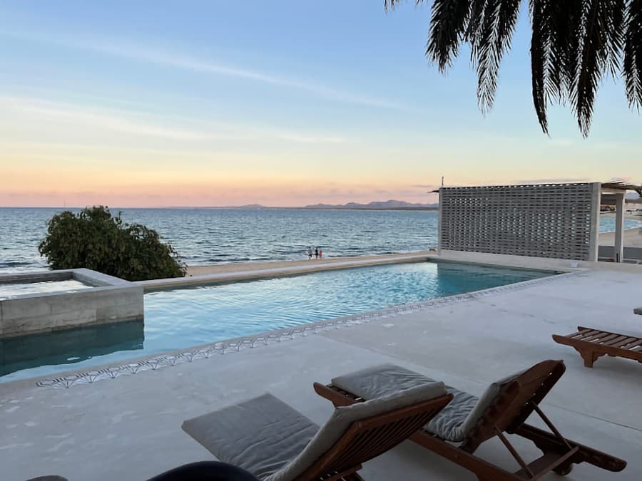 A serene infinity pool overlooks the ocean at sunset.